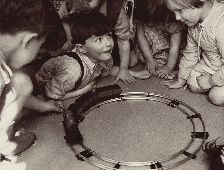 Black and white photograph of a group of children playing with a trainset
