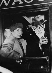 Black and white photograph of Anna and Sigmund Freud looking out of a train window.