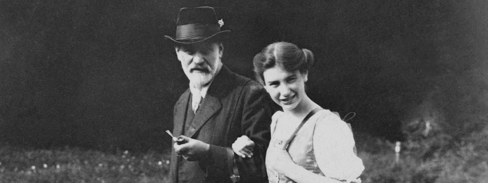 Black and white photograph of Sigmund and Anna Freud walking arm in arm and looking at the camera